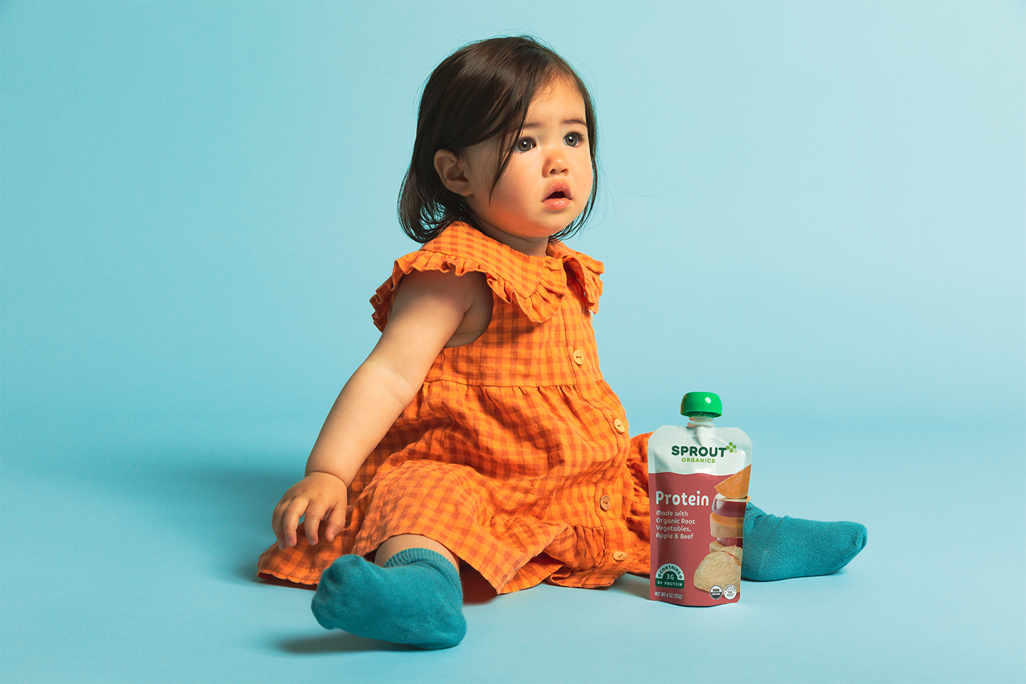 child sitting in a chair holding a sprout organics protein pouch